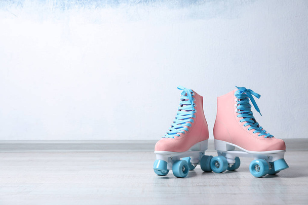 Vintage roller skates on floor near color wall. Space for text - Foto, imagen