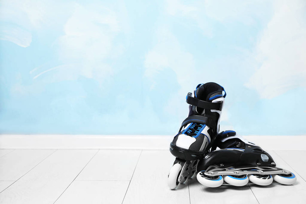 Inline roller skates on floor near color wall. Space for text - Foto, Bild