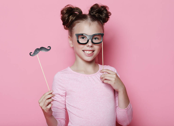 Girl pose with photo booth props glasses and mustache. Child girl with party glasses over pink background. - Foto, Imagem