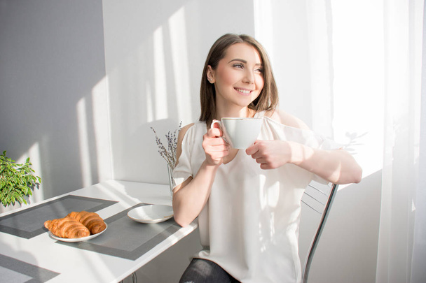 onnellinen tyttö on aamiainen croissants ja kahvia
 - Valokuva, kuva