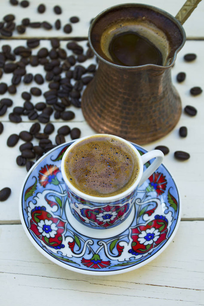 Турецкая чашка кофе, кофейник и кофейные зерна на деревянном белом фоне
. - Фото, изображение