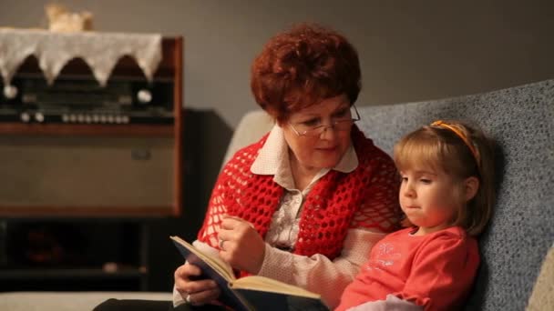 Babička čte pohádku své malé vnučce. Rodinné čtení volného času - Záběry, video