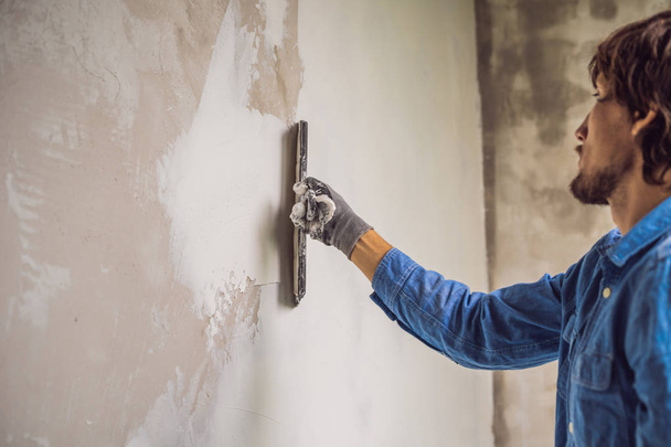 Master applying white putty on wall and smearing by putty knife. - Fotoğraf, Görsel