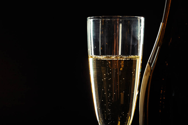 bottle of champagne and glasses over dark background - Foto, afbeelding