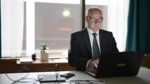 Happy Senior Businessman Using Phone And Laptop At Work - Materiał filmowy, wideo