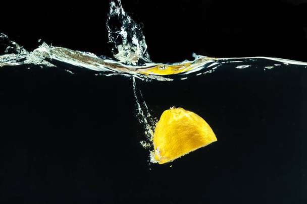 fresh yellow lemon in water splash on black background - Фото, изображение