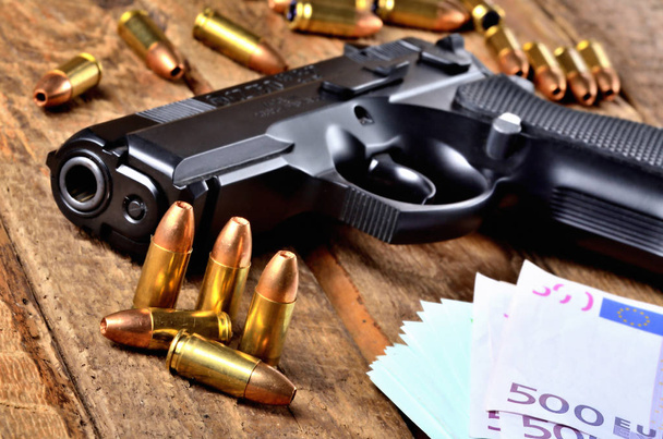 Primer plano de la pistola de 9 mm, balas huecas especiales de la policía en expansión y billetes en euros en la vieja mesa de madera - vista al barril
 - Foto, imagen