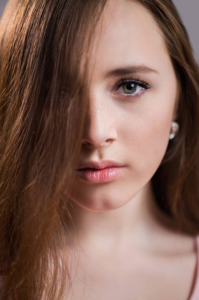 Closeup face of a beautiful redhead young woman with freckles. Charming girl with clean skin, natural beauty looks into the camera. Neat eyebrows - Photo, Image