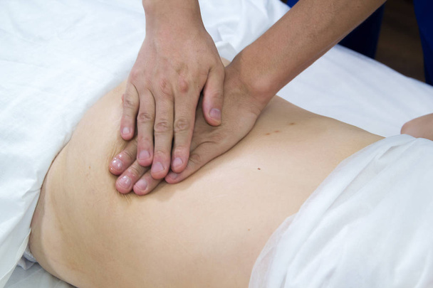 A woman taking a treatment of alternative medicine. Belly massage. Close up - Фото, изображение