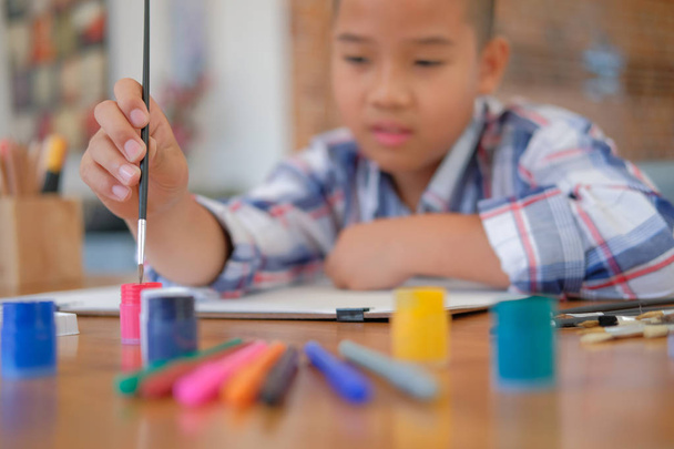 kleine asiatische Junge Kind Schuljunge mit Pinsel Zeichnung Malerei Aquarell. Freizeitaktivitäten für Kinder zu Hause - Foto, Bild