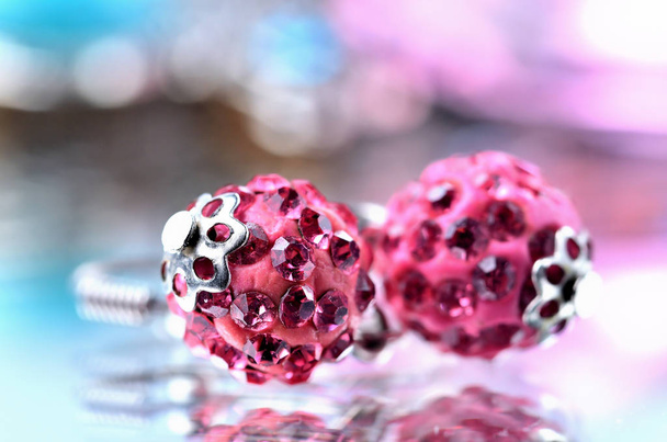 Close-up van rode oorbellen met rode diamanten juwelen - reflectie effect - twee gekleurde achtergronden - blauw, paars - Foto, afbeelding
