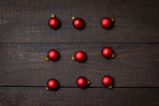 Σκοτεινό ρουστίκ ξύλινος πίνακας flatlay - χριστουγεννιάτικο φόντο με κόκκινο Χριστουγεννιάτικα στολίδια. Το Top view με ελεύθερο χώρο για αντιγραφή κειμένου - Φωτογραφία, εικόνα