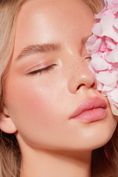 beautiful blonde model with nude makeup and pink flowers, close-up - Fotó, kép
