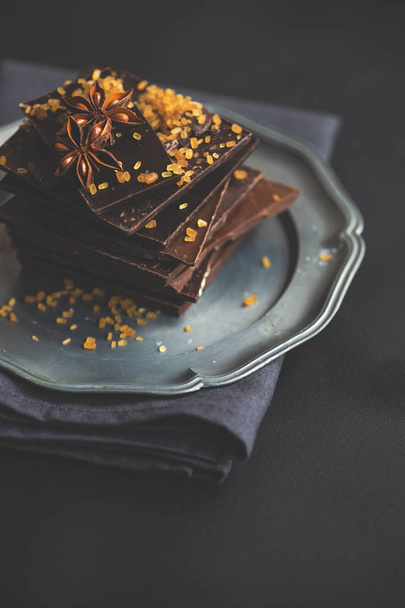 Ciemne kawałki czekolady zgnieciony na ciemny drewniany stół, przyprawy jak cynamon i anyżu star jako koncept gastronomiczny z kopia przestrzeń, widok z góry - Zdjęcie, obraz