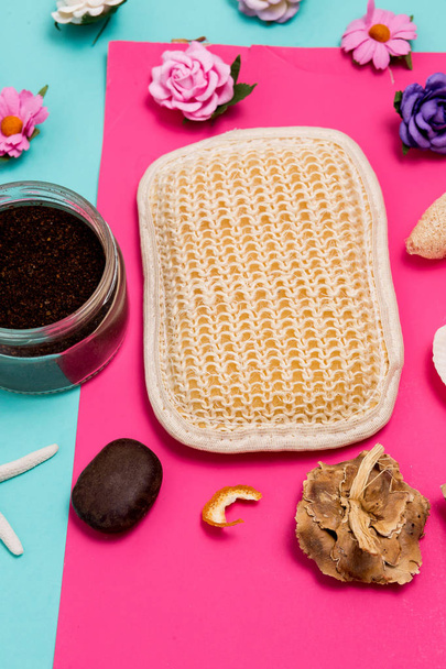 Close up of spa and beauty cosmetics products on colorful blue and pink background. Body and face scrub, natural loofah washcloth, shells, stones and flowers - Φωτογραφία, εικόνα