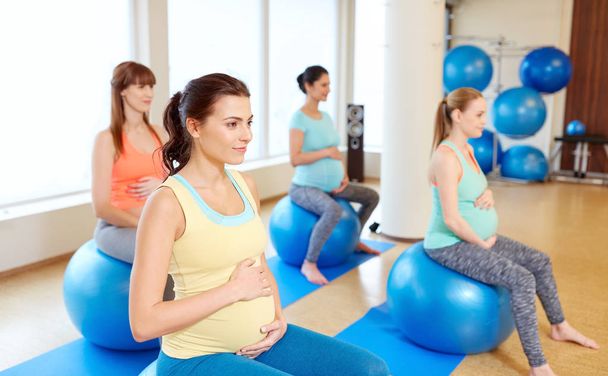 pregnant women sitting on exercise balls in gym - Foto, afbeelding