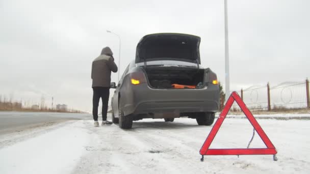 冬の運転。車のトラブル。雪国の道路での車のトラブル。若い男を呼び出してレスキュー サービス - 映像、動画
