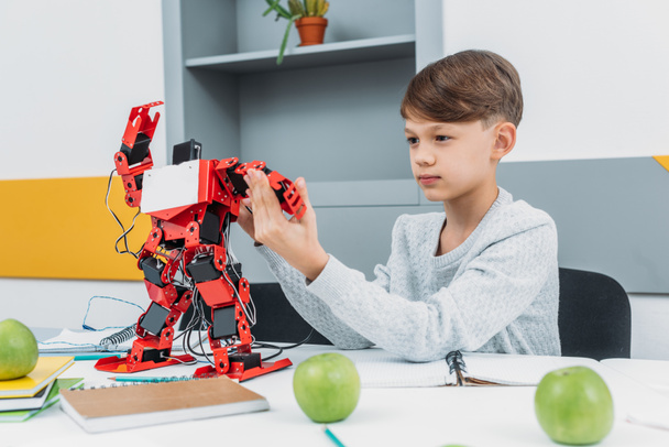 προσεκτικός αγόρι που εργάζονται με ένα ρομπότ στο μάθημα ρομποτική βλαστικών - Φωτογραφία, εικόνα
