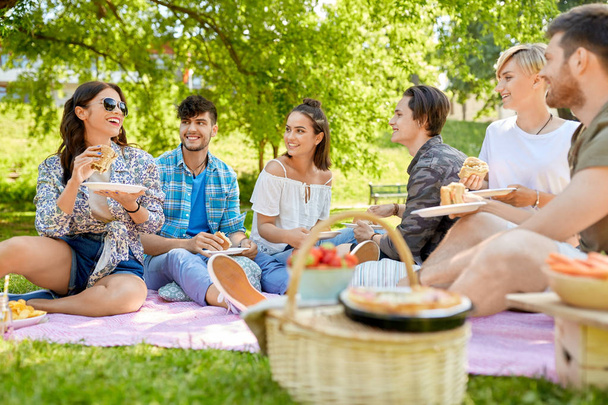 happy friends eating sandwiches at summer picnic - Φωτογραφία, εικόνα