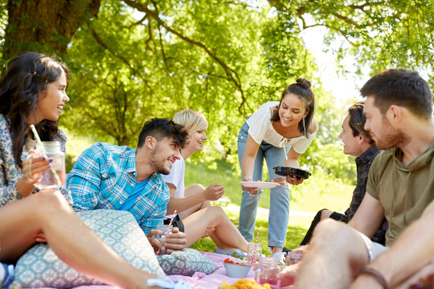 friends with drinks and food at picnic in park - Φωτογραφία, εικόνα