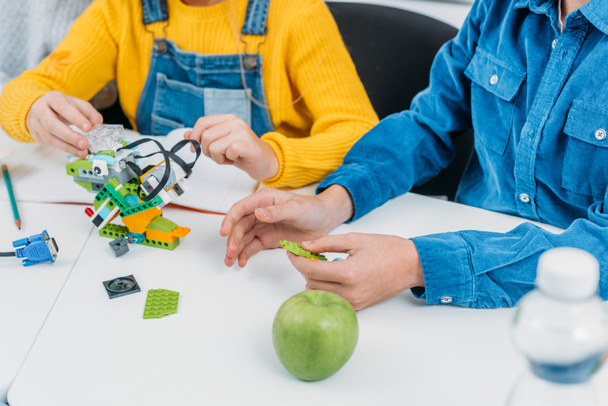 cropped view of schoolchildren making robot with details at desk in stem class - Valokuva, kuva