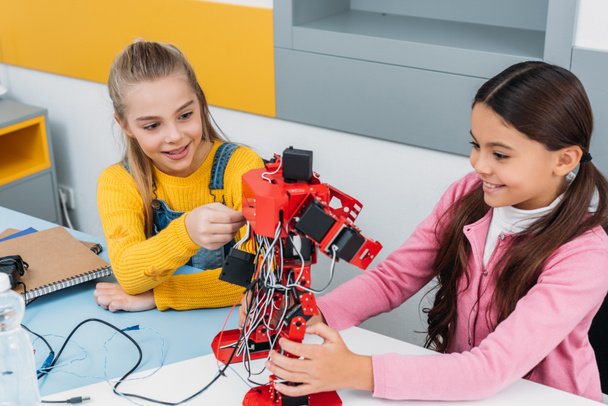 sorrindo alunas tocando robô artesanal vermelho na classe tronco
 - Foto, Imagem