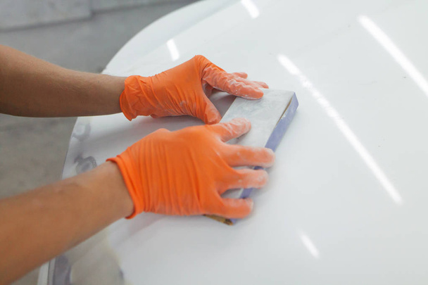 men's hands in orange gloves take the form of the hood for the subsequent eipoking of the car. man working in a car garage - Photo, image