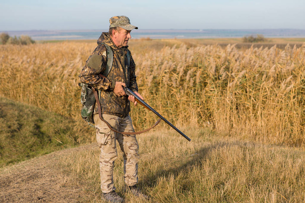 Hunter with a gun and a dog go on the first snow in the steppe, Hunting pheasant in a reflective vest - Photo, Image