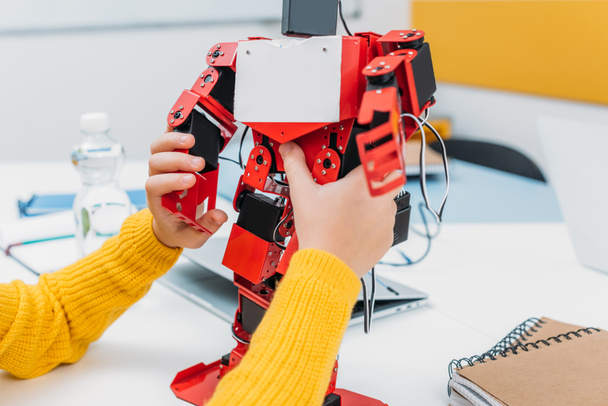 cropped view of schoolkid playing with robot model at STEM educational class - 写真・画像