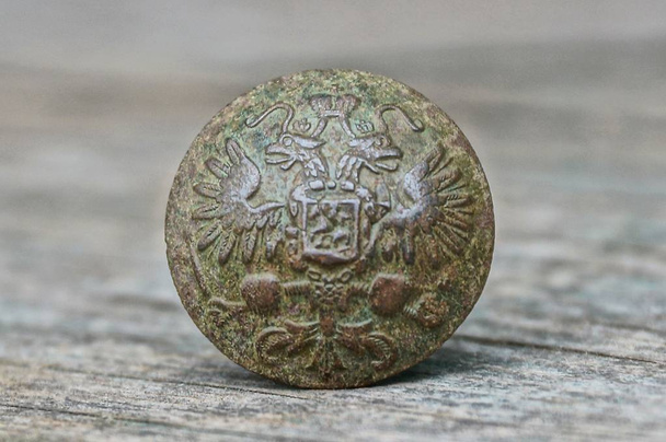 um botão de latão velho com emblema e águia em uma mesa cinza
 - Foto, Imagem