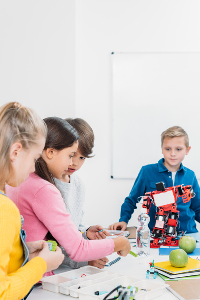 schoolchildren programming robot together during STEM educational class - Photo, Image
