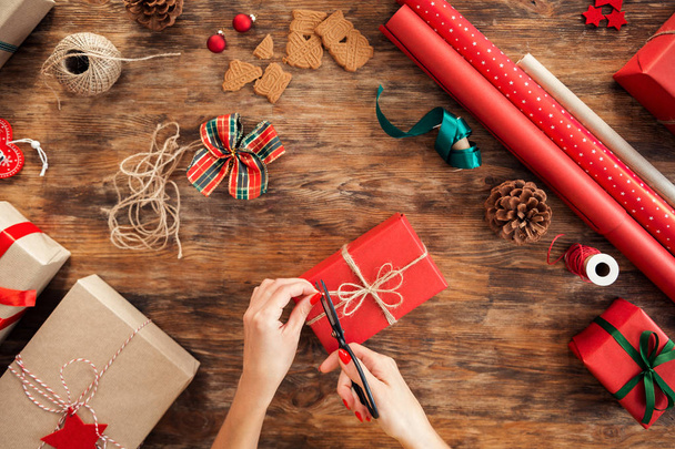 DIY Gift Wrapping. Woman wrapping beautiful red christmas gifts on rustic wooden table. Overhead point of view of christmas wrapping station. - Foto, Imagem