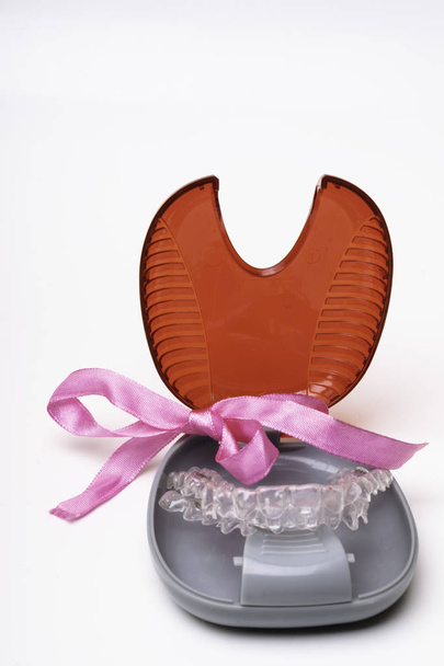 Geïsoleerde transparante tanden prothese aligner met haar aansluitdoos, boog, gift of heden. Een manier om een mooie glimlach - Foto, afbeelding