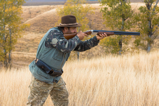 Jäger mit Hut und Gewehr auf der Suche nach Beute in der Steppe, zielt auf Beute - Foto, Bild