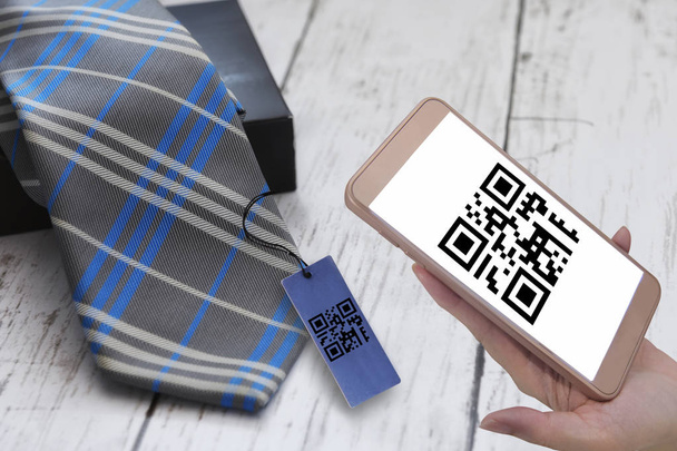 Ręka gospodarstwa smartphone rezygnować skanowanie Qr kod znak ekranu z krawat na białym tle drewnianych, inteligentna technologia koncepcji i qr kod pomysł - Zdjęcie, obraz