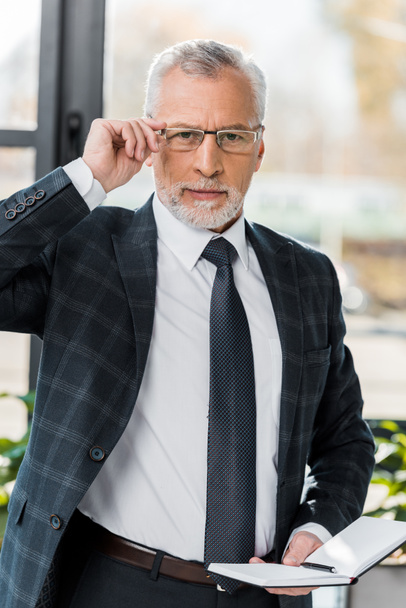 confiant homme d'affaires mature ajuster les lunettes et regarder la caméra
 - Photo, image