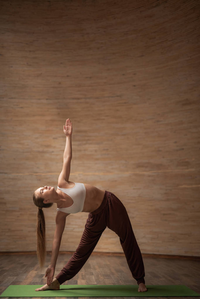 Calm young lady practicing revolved triangle pose at yoga class - Foto, Imagem