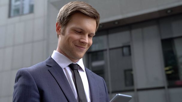 Delighted young businessman receiving good news, scrolling application on phone - Foto, Imagen
