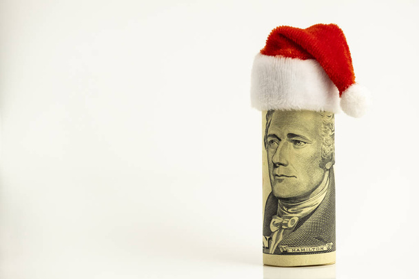President Hamilton in the role of Santa Claus. Humorous concept. The ten dollar bill of the USA is twisted into a tube and a red cap at the top. New Year or Christmas financial surprise. White background. Copy space. - Photo, Image