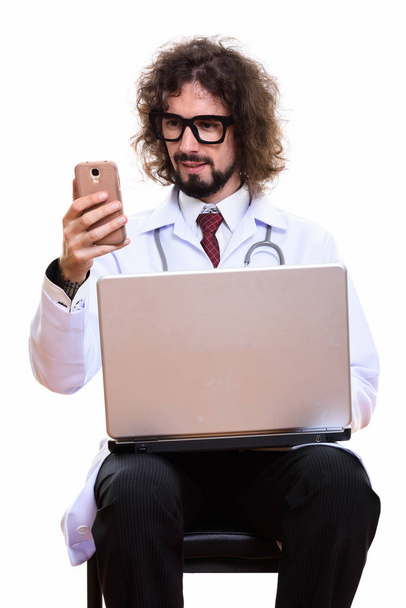 Szczęśliwy człowiek lekarz uśmiechnięty podczas korzystania z telefonu komórkowego z laptopem - Zdjęcie, obraz