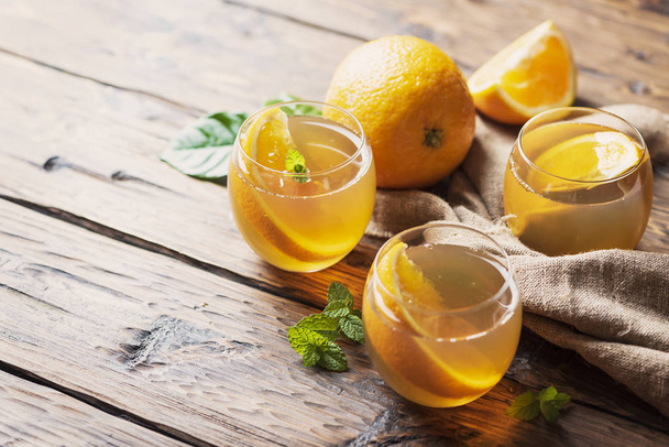 Cold tea with orange and mint on the wooden table, selective focus - Zdjęcie, obraz