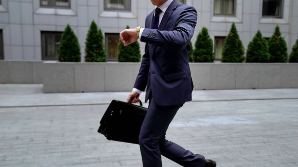 Office worker looking at watch late for work, lack of self-organization, traffic - 写真・画像