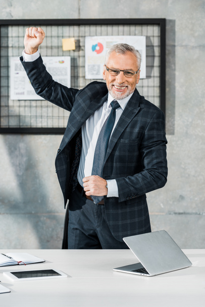 happy handsome middle aged businessman gesturing and looking at camera in office - Fotoğraf, Görsel