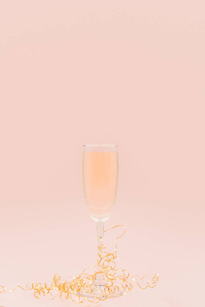 A glass of champagne with bubbles. Christmas balls and a golden lights on light abstract background. - Photo, Image