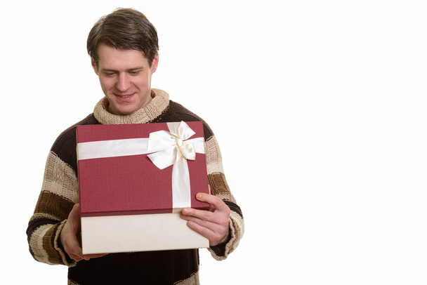 Onnellinen komea valkoihoinen mies avaamalla lahjapakkauksen valmis Valentin
 - Valokuva, kuva