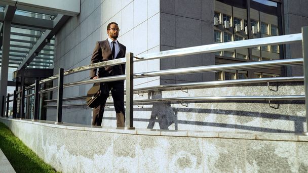 Gerente afroamericano saliendo del centro de negocios después de una reunión exitosa, rutina
 - Foto, Imagen