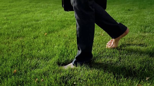 Male walking barefoot on green grass, relaxing after work, dreams about holiday - Foto, afbeelding