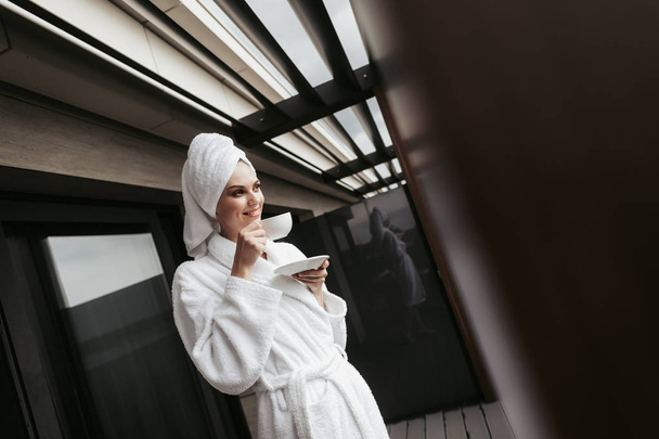 Young woman in bathrobe with cup of tea - Foto, Bild