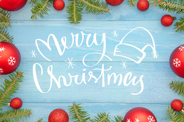 Vue du dessus de l'écriture Joyeux Noël sur une table en bois bleu rustique avec arbre de Noël et boules rouges. Carte de voeux saisonnière des vacances d'hiver. À Noël. Pose plate
 - Photo, image