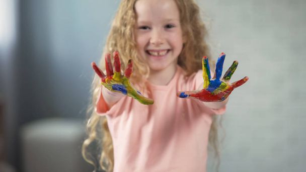 Šťastná dívka s malovanými dlaně úsměv do kamery a smějící se, šťastné dětství - Fotografie, Obrázek